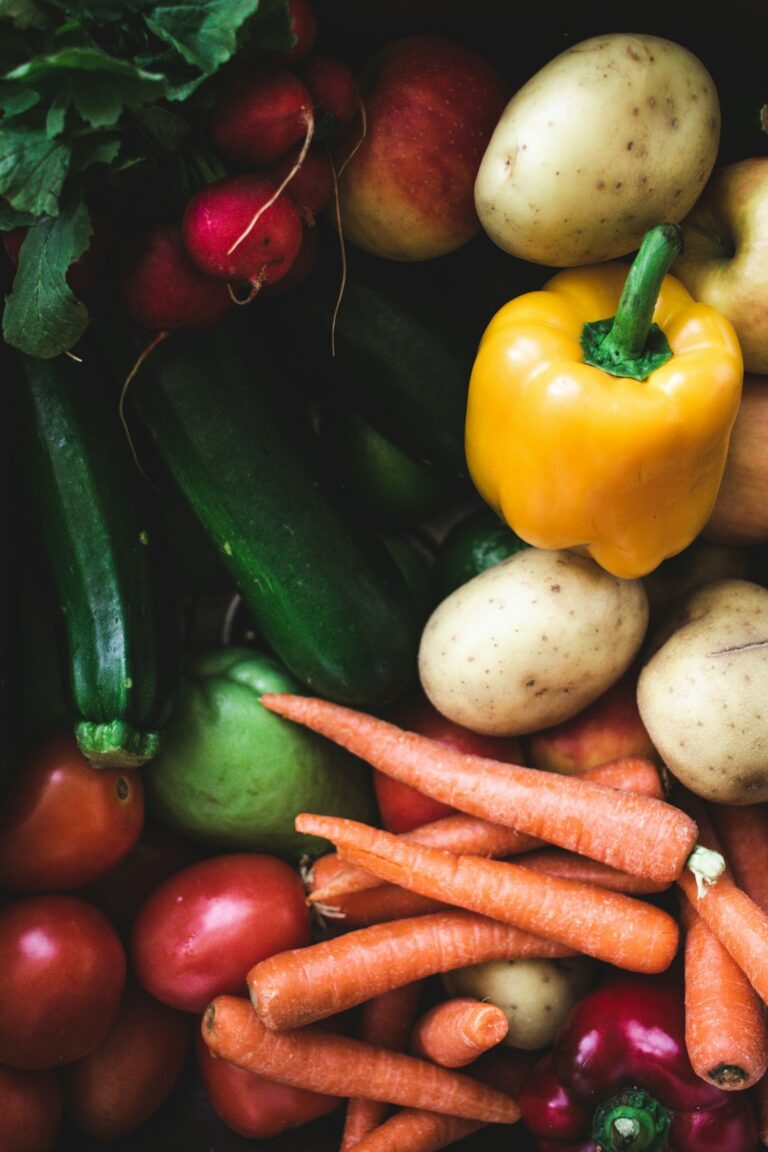 A family preparing a colorful salad together at a kitchen table, with fresh vegetables and leafy greens.